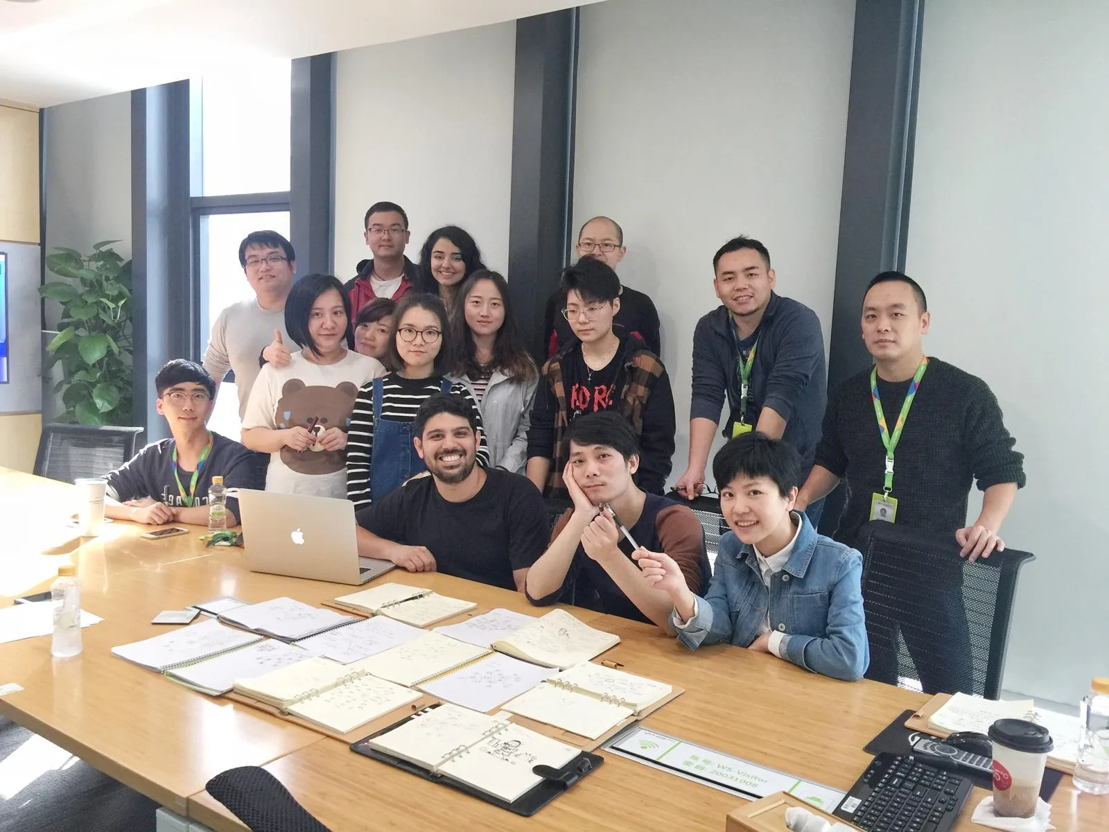 Terry with a design team at a table covered in notebooks with icon sketches, after a workshop he ran.